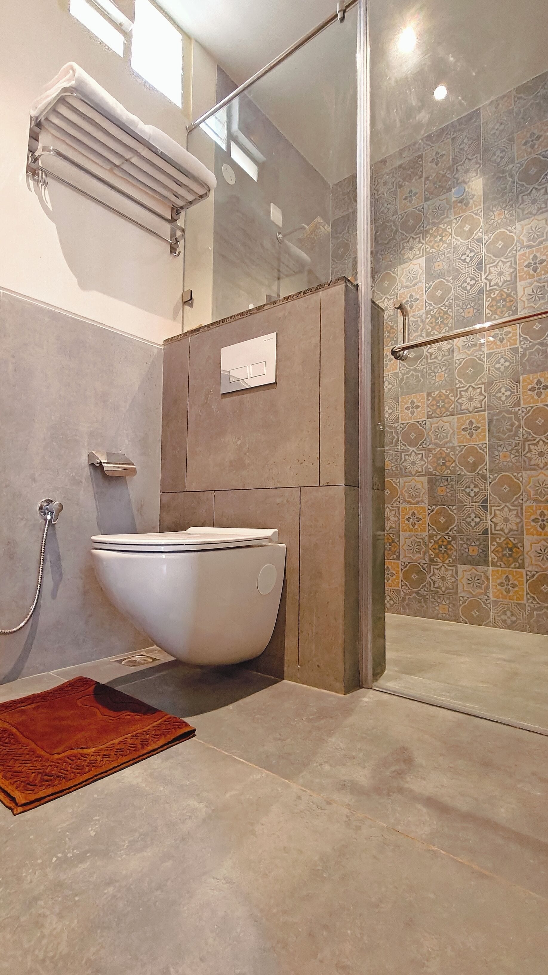 Une salle de bain moderne avec une baignoire sur pieds, une douche à parois de verre et des murs recouverts de carreaux à motifs.