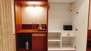 Habitación pequeña y bien iluminada con tocador de madera, lavamanos y estante con una radio.