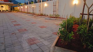 Un espacio al aire libre empedrado, con un muro blanco y plantas.