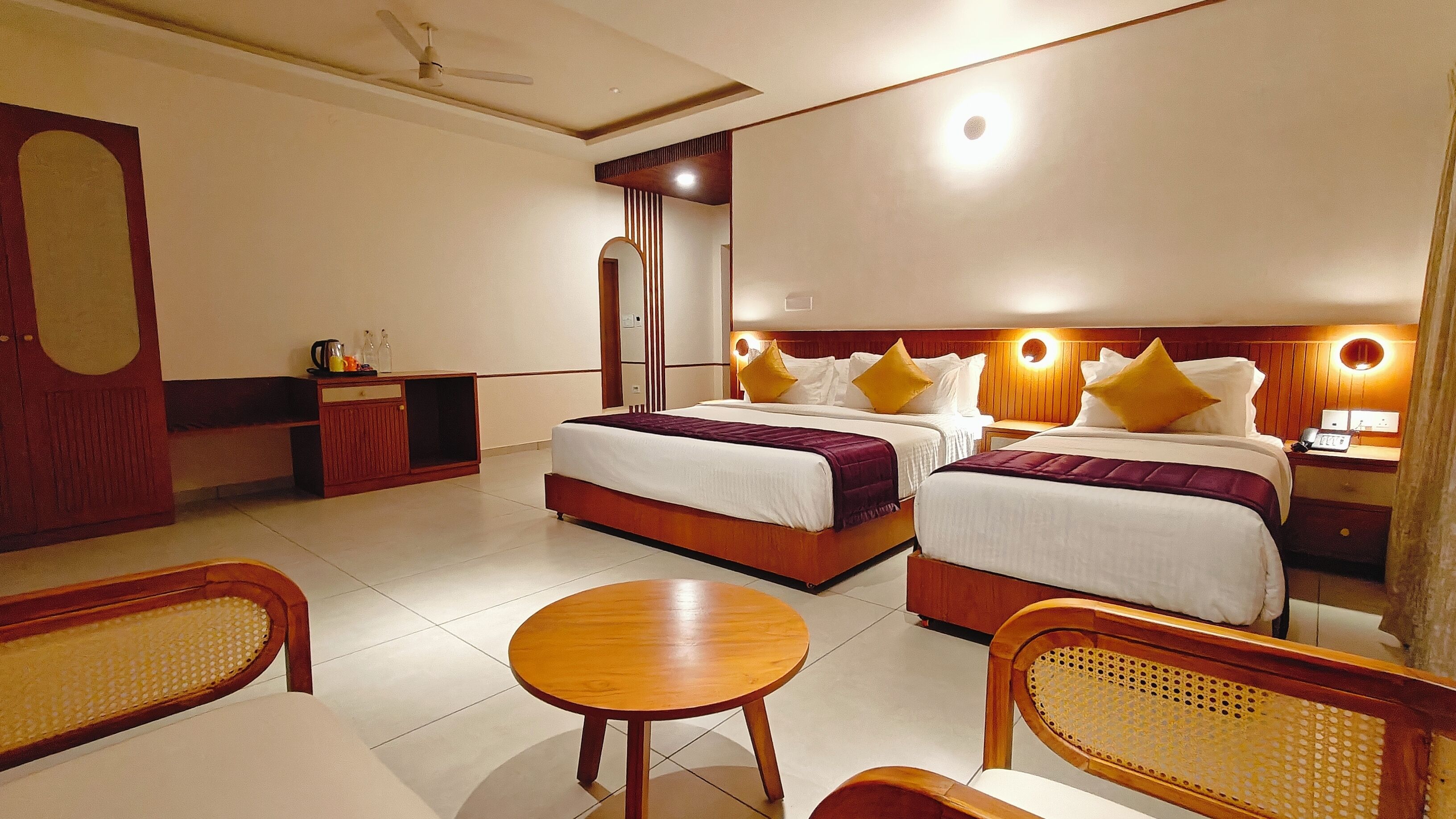 A hotel room with two beds, a desk, a chair, and a round table.