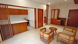 Un espacio habitable compacto con kitchenette, una zona de comedor con dos sillas y una mesita.