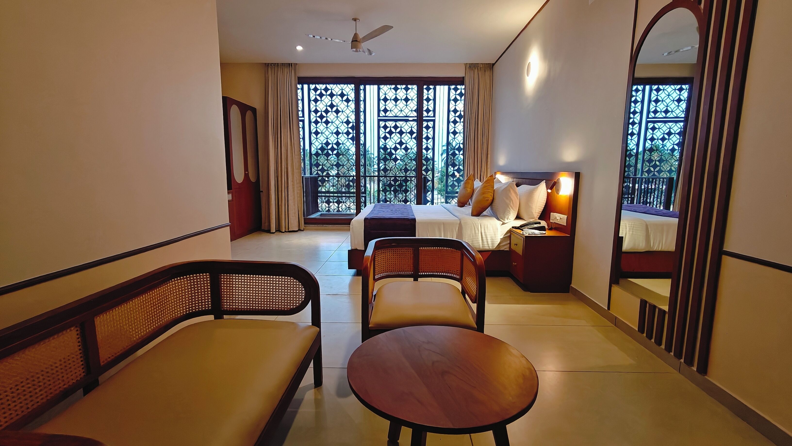 A hotel room with a bed, a desk, a chair, a table, and a large window with a view.