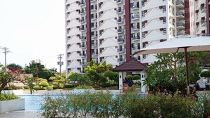 Un edificio residencial de gran altura con varios balcones, piscina y jardines ajardinados.