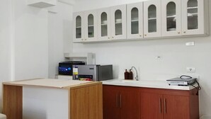 Una cocina moderna con armarios blancos, encimera de madera y refrigerador empotrado.