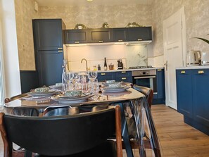 Eine moderne Küche mit dunklen Schränken, einem Esstisch gedeckt mit Tellern und Gläsern, sowie einer Kaffeemaschine.