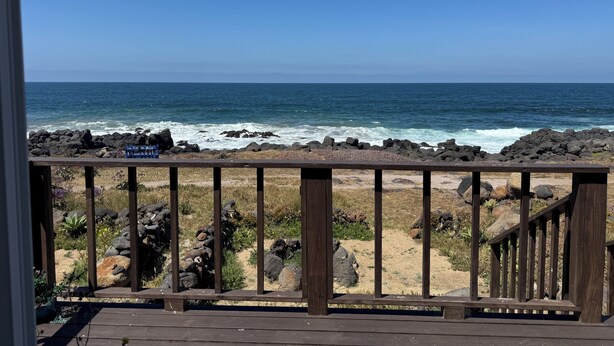 Eine Holzterrasse mit Blick auf das Meer und eine felsige Küstenlinie.