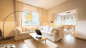 Ein modernes Wohnzimmer mit Sofa, Couchtisch und einem Essbereich mit Stühlen und Tisch.