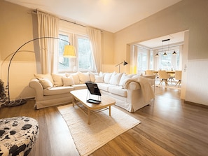 Ein modernes Wohnzimmer mit Sofa, Couchtisch und einem Essbereich mit Stühlen und Tisch.