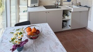 Een keuken met een wit aanrecht, een spoelbak, een magnetron en een raam.