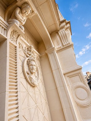 Fachada d'edifici amb detalls arquitectònics clàssics, incloent un relleu esculpit i motllures decoratives.