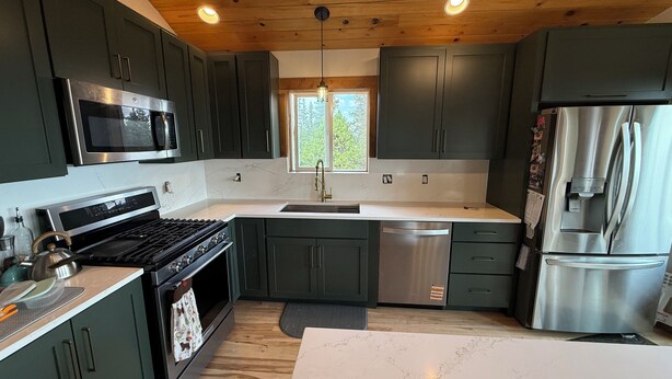 A modern kitchen with dark cabinets, stainless steel appliances, a marble countertop, and a wooden ceiling. - Best View in Fairplay (Fairplay)