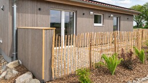 Un edificio moderno con rivestimento in legno, ampie porte scorrevoli in vetro e un’area esterna recintata.