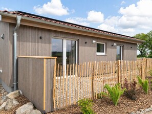 Ein modernes Gebäude mit Holzfassade, großen Schiebeglastüren und einem eingezäunten Außenbereich.