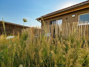 Una construcción de madera con patio cercado, una ventana y una puerta.