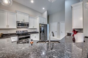 A modern kitchen with white cabinets, stainless steel appliances, granite countertops, and a stainless steel sink. - Luxury Cape Coral Oasis: Pool, Sleeps 8 (Cape Coral)