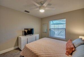 A bedroom with a bed, a TV on a dresser, a ceiling fan, and a window with blinds. - Luxury Cape Coral Oasis: Pool, Sleeps 8 (Cape Coral)