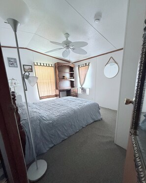 A bedroom with a bed, a ceiling fan, a desk, a chair, a lamp, and a mirror. - 5 Peaceful Acres•Pet Friendly•Short Drive to Beach (Milton)