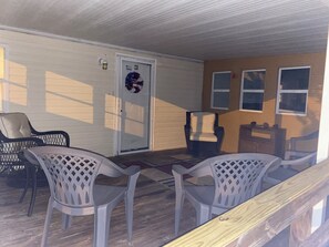 A covered porch with plastic chairs, a wicker chair, and a door with a wreath. - 5 Peaceful Acres•Pet Friendly•Short Drive to Beach (Milton)