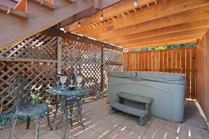 A patio with a round table, two chairs, a bottle of wine, and a hot tub. - Mtn Retreat Hot Tub~Lake 20 min (Mi-Wuk Village)