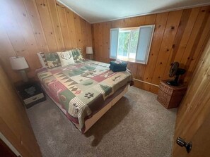 A bedroom with a bed, a nightstand, a lamp, a window, and a fan. - Mtn Retreat Hot Tub~Lake 20 min (Mi-Wuk Village)