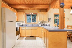 A kitchen with wooden cabinets, a refrigerator, a microwave, a sink, and a coffee maker. - Wildwood Snowline Cabin Near Mt Baker (Deming)