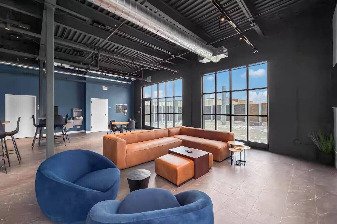 A modern lounge area with a sectional sofa, blue bean bag chairs, and a small coffee table.