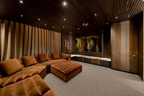 Een moderne woonkamer met een hoekbank, een flatscreen televisie en een houten plafond.