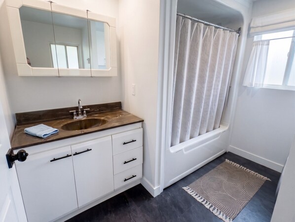 A bathroom with a sink, mirror, and shower curtain.