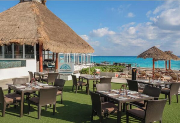 A resort with thatched-roof structures, outdoor dining areas, and a view of the ocean. - NEW YEAR'S WEEK in Cancun - Ocean View Westin Studio - Dec 27–Jan 2 - Sleeps 4 (Cancun)