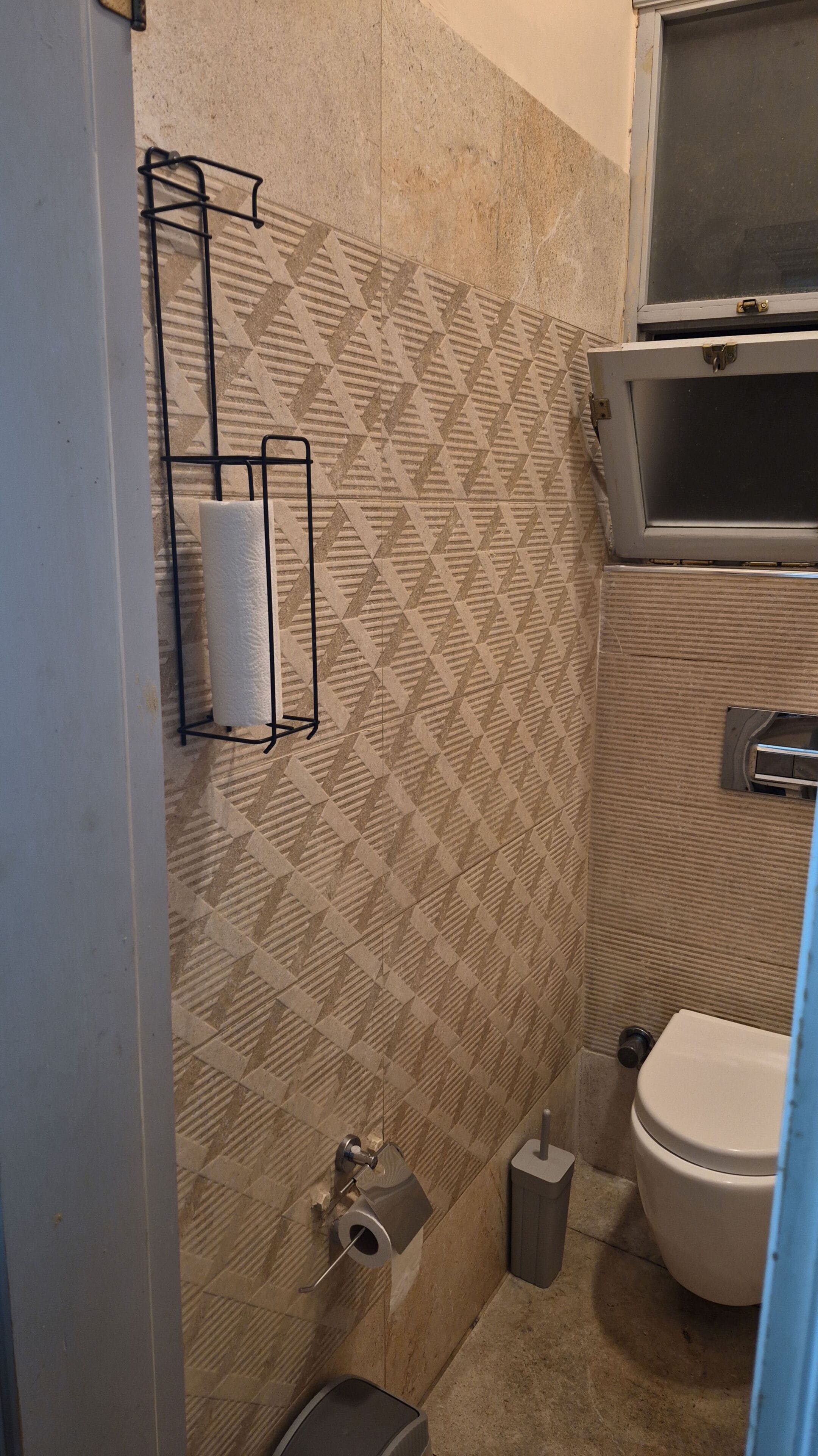 Un baño con baldosas estampadas, inodoro, bidé y un perchero.