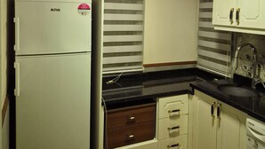 A compact kitchen with a refrigerator, a washing machine, and a sink.