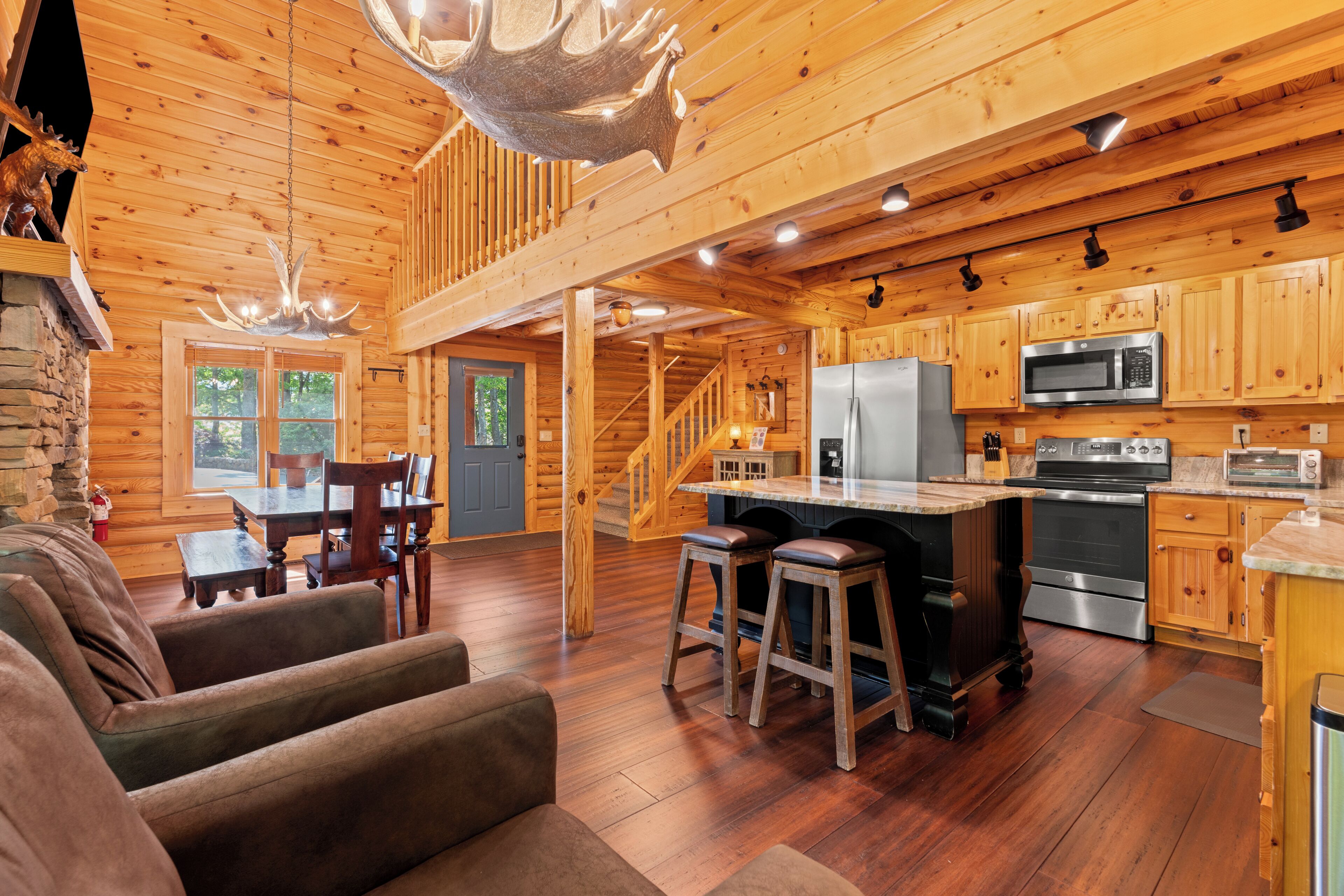 A log cabin interior with a dining area, kitchen, and a staircase.