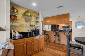 A kitchen with wooden cabinets, a black countertop, a coffee machine, and a clock on the wall. - Gorgeous 2-bedroom condo with beautiful pool, hot tub, and more in Hot Springs (Hot Springs)