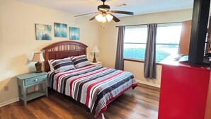 A bedroom with a bed, a nightstand, a ceiling fan, a window with curtains, and a red cabinet. - Gorgeous 2-bedroom condo with beautiful pool, hot tub, and more in Hot Springs (Hot Springs)