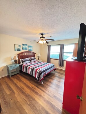 A bedroom with a bed, a nightstand, a ceiling fan, a window with curtains, and a red cabinet. - Gorgeous 2-bedroom condo with beautiful pool, hot tub, and more in Hot Springs (Hot Springs)