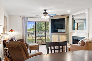 A living room with a TV, fireplace, and a view of an outdoor pool. - Gorgeous 2-bedroom condo with beautiful pool, hot tub, and more in Hot Springs (Hot Springs)