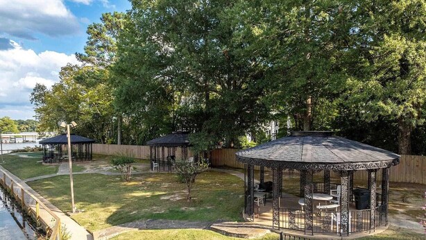 A fenced backyard with a gazebo, a small lawn, and a body of water. - Gorgeous 2-bedroom condo with beautiful pool, hot tub, and more in Hot Springs (Hot Springs)