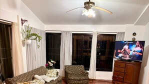 Una sala de estar con sofá, sillón, televisor y mesa de comedor.