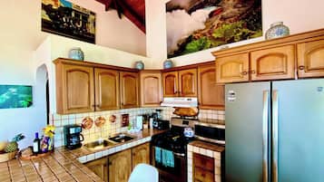 Une cuisine avec des meubles en bois, un réfrigérateur en acier inoxydable, un pare-feu en carrelage et un grand tableau accroché au mur.