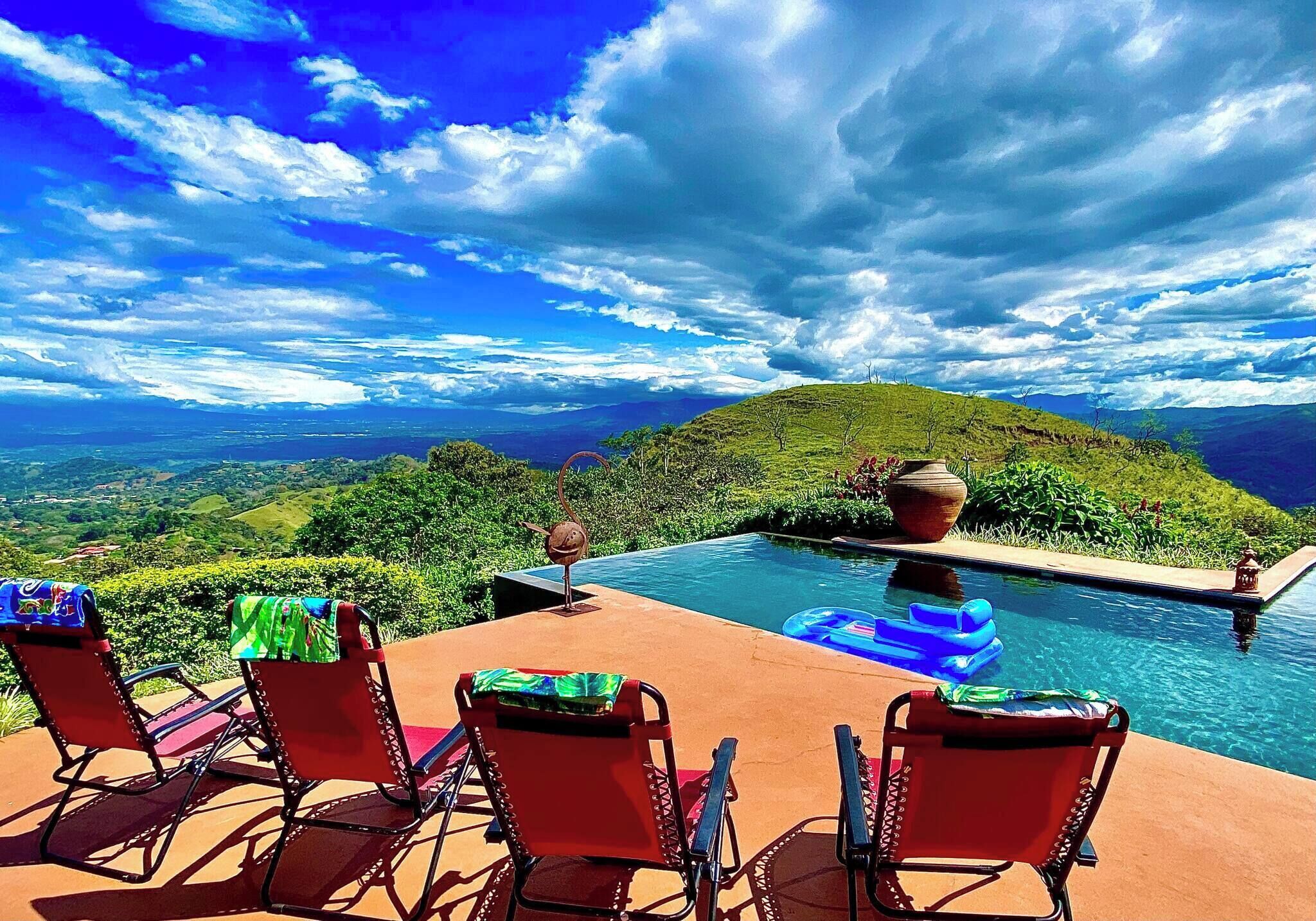 Zona de piscina con sillas y vista a un paisaje montañoso.