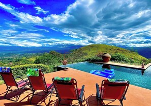 Zona de piscina con sillas y vista a un paisaje montañoso.