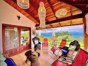 A spacious patio with wicker furniture, a glass table, and a view of the landscape.