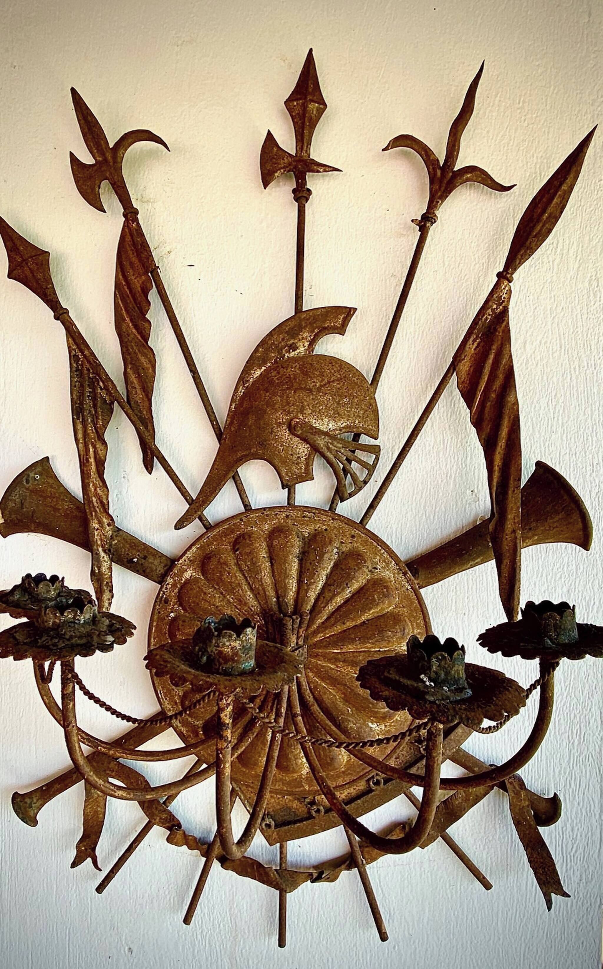 A wall-mounted decorative metal piece with a central circular element surrounded by various shapes and figures.