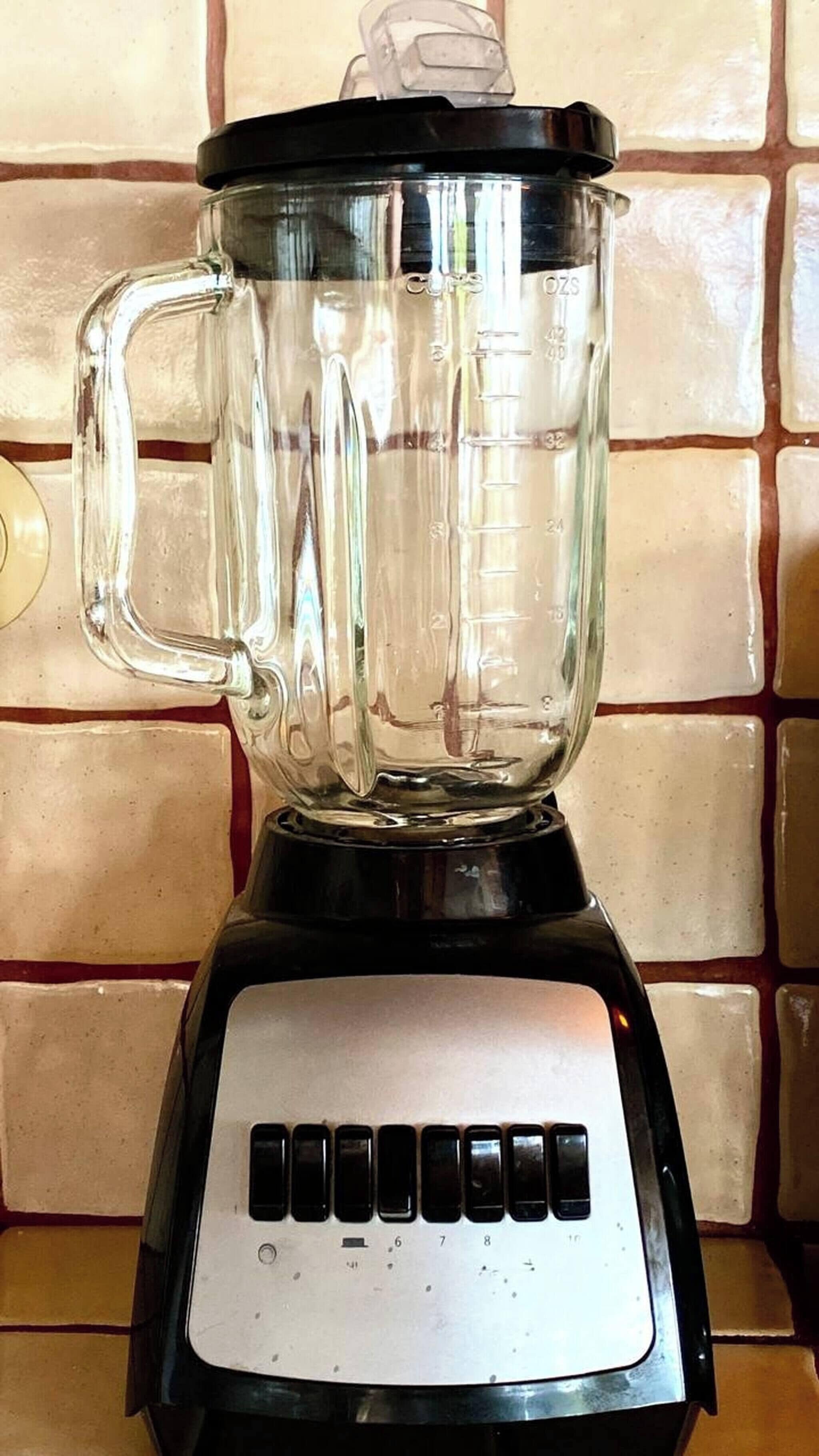 A kitchen blender with a clear pitcher and a black base, placed on a tiled countertop.