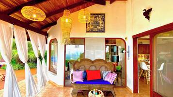 A room with a wicker sofa, a patterned rug, and a view through a glass door.