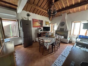 A kitchen with a dining table, chairs, a refrigerator, a stove, and a chandelier. - Villa i Cipressi, Riva del Po, FE (Riva del Po)