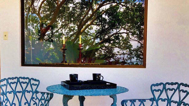 Una habitación con una mesa redonda, dos sillas y un ventanal con vistas a árboles.