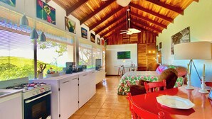 Una cocina con estufa a gas, un comedor con mesa roja y un ventilador de techo.