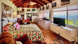 Una habitación acogedora con cama, escritorio, televisor y ventana con persianas.