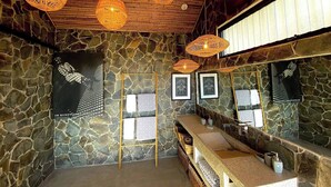 Un baño con paredes de piedra, techo de madera y lámparas de fibra.